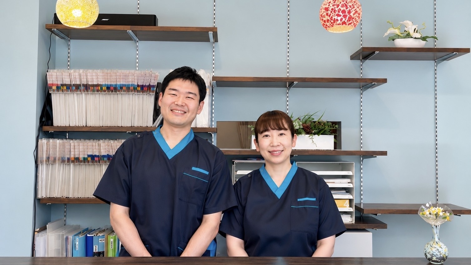 勝田台ほぐし接骨院の受付に立つ夫婦スタッフ